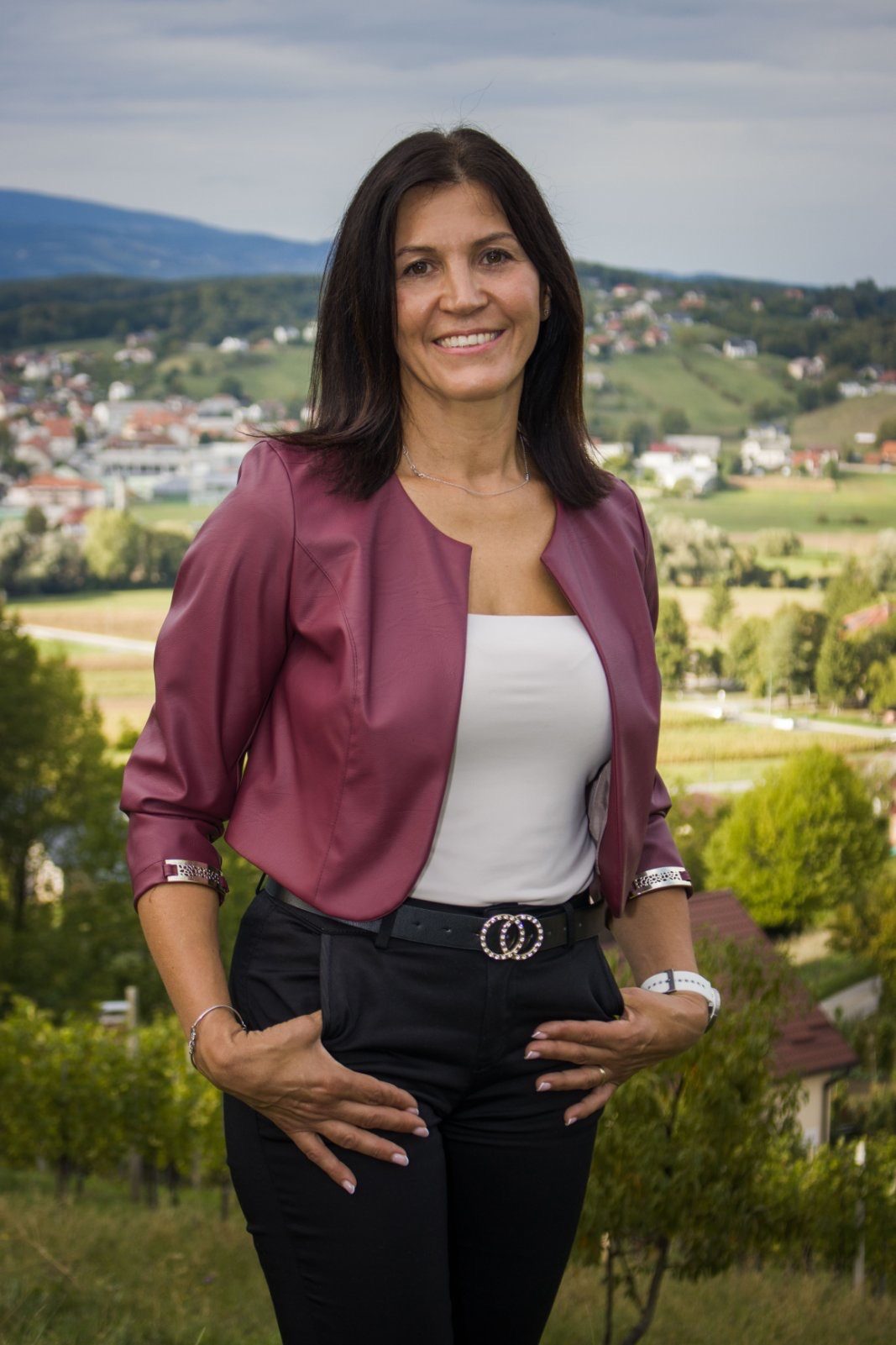 Klavdija Majer v bordo jakni stoji na travniku nad Poljčanami